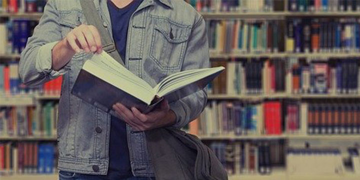 boy in library holding a book