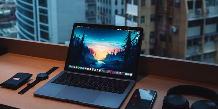 macbook on a desk in front of a window